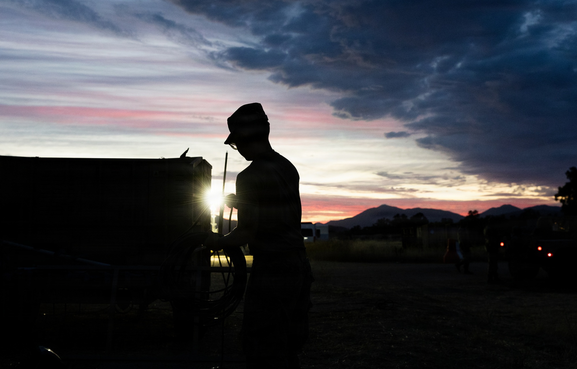 Soldier silhouetted against a sunset sky during field operations