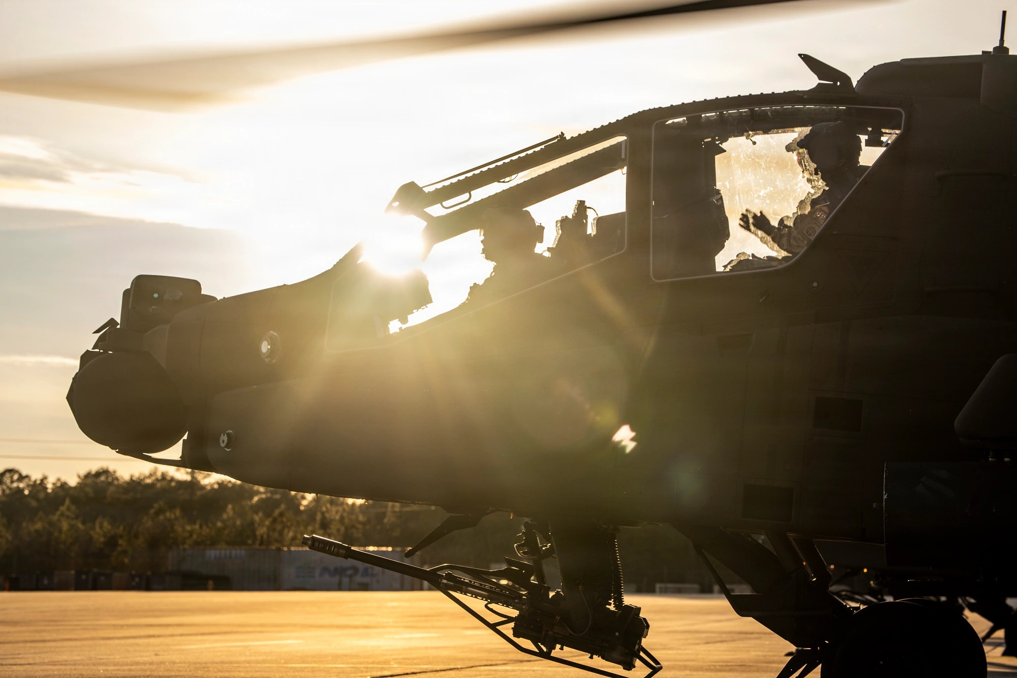 Silhouette of an AH-64 Apache pilot in the cockpit during pre-flight checks at sunset