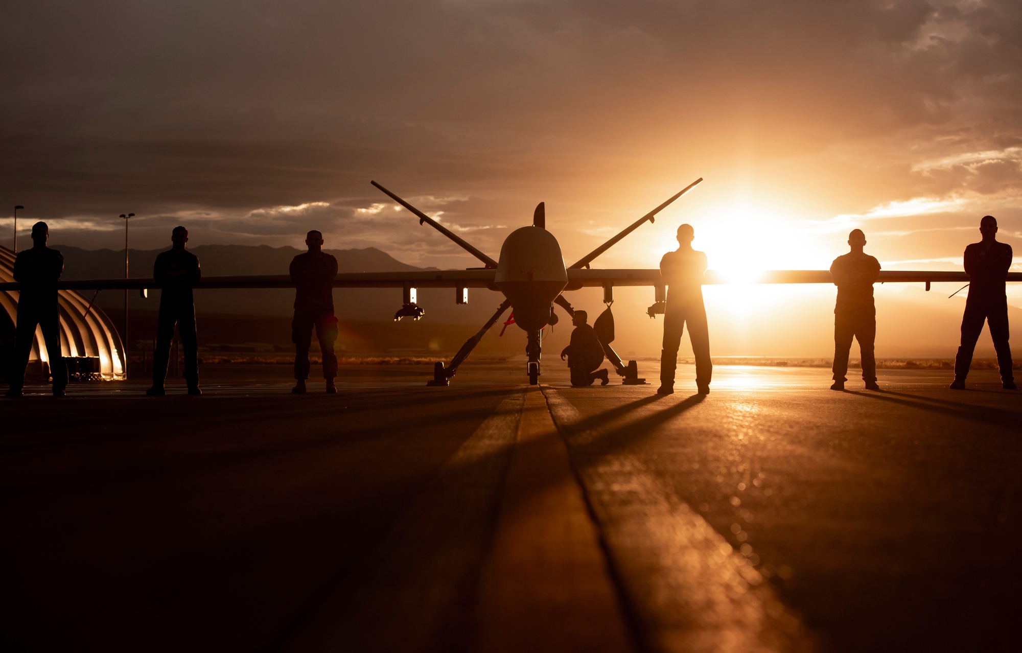 MQ-9 Reaper and aircrew silhouetted against a Nevada sunset